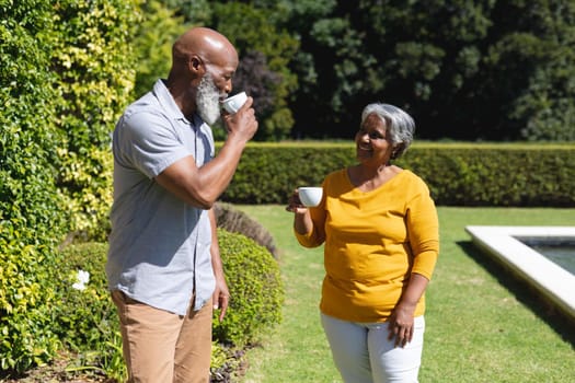 Senior african american couple spending time in sunny garden together drinking coffee. retreat, retirement and happy senior lifestyle concept.