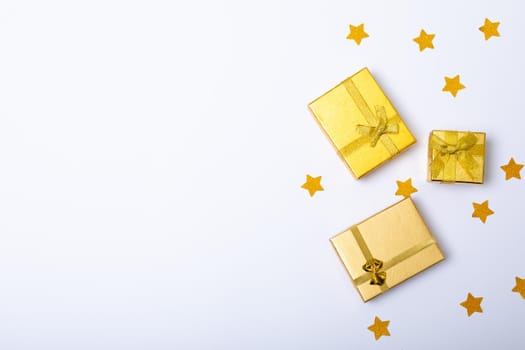 Composition of gold presents with stars and copy space on white background. christmas, tradition and celebration concept.