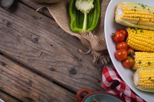 Composition of autumn halloween corn, tomatoes and pepper with copy space on wooden background. autumn, halloween tradition, food, cooking and celebration concept.