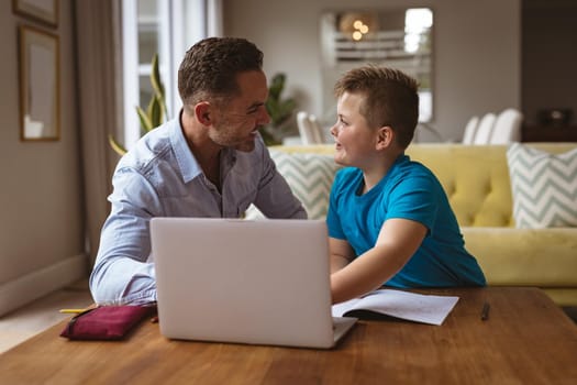 Caucasian father using laptop to help his son with homework at home. home schooling and education concept