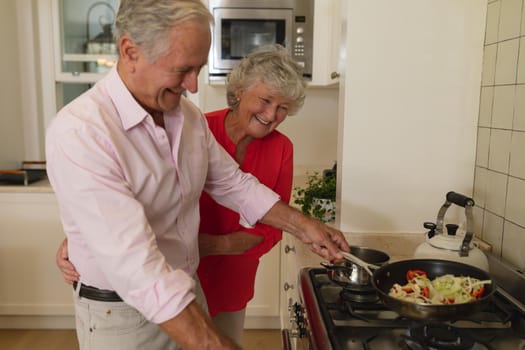 Senior caucasian couple cooking together and smiling in kitchen. retreat, retirement and happy senior lifestyle concept.