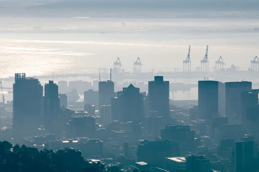 General view of cityscape with multiple modern buildings and cranes in the foggy morning. skyline and urban architecture.