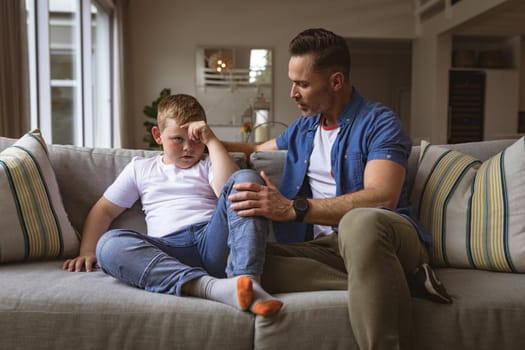 Caucasian father scolding his son sitting on the couch at home. fatherhood and childhood concept