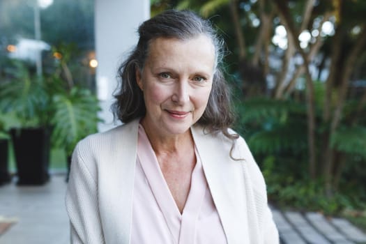 Portrait of happy senior caucasian woman looking to camera and smiling in garden. retirement lifestyle, spending time alone at home.