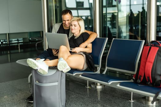 Traveling concept. Waiting for boarding. Happy loving couple in casual wear in airport terminal holding passport with tickets