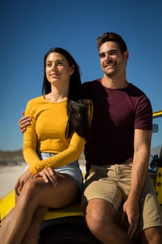 Happy caucasian couple woman sitting in beach buggy by the sea both looking ahead. beach break on summer holiday road trip.