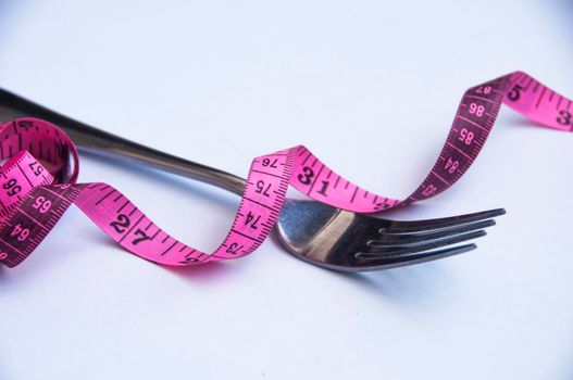 Measuring tape with fork on white background. Weight loss and fitness concept