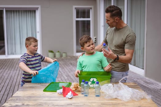 Caucasian father and two sons collecting plastic materials in a bag outdoors. plastic recycling and pollution control concept