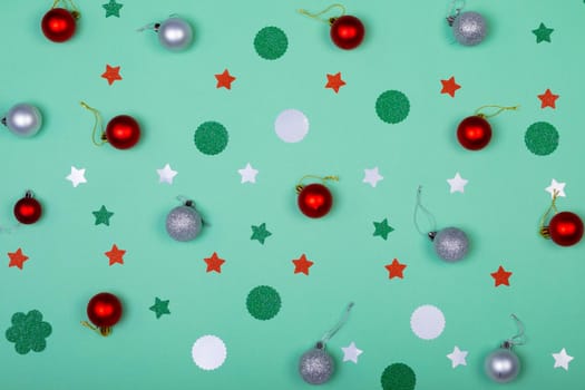Composition of christmas decorations with baubles and stars on green background. christmas, tradition and celebration concept.