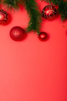 Composition of garland with baubles and copy space on red background. christmas, tradition and celebration concept.