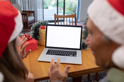 Caucasian woman and senior man having video call on laptop with copy space at christmas time. christmas, festivity and communication technology at home.