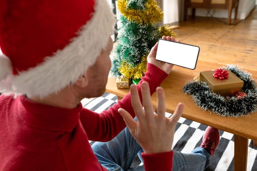 Albino african american man wearing santa hat making video call on smarphone with copy space. christmas, festivity and communication technology festivity and communication technology.