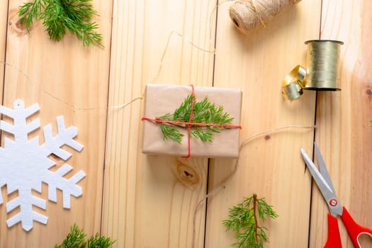 Composition of christmas decorations with present, ribbon, and scissors on wooden background. christmas, tradition and celebration concept.