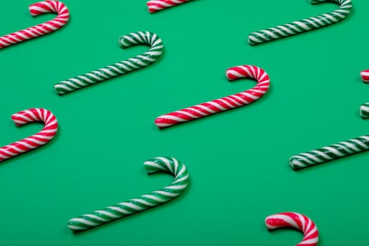 Composition of multiple green and red candy canes on green background. christmas, tradition and celebration concept.
