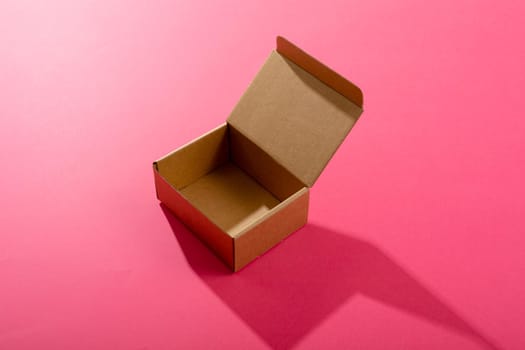 Composition of open empty cardboard gift box on pink background. christmas, gift, tradition and celebration concept.