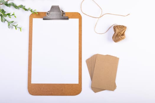 Composition of clipboard with copy space and envelopes, string, branches on white background. christmas, tradition and celebration concept.