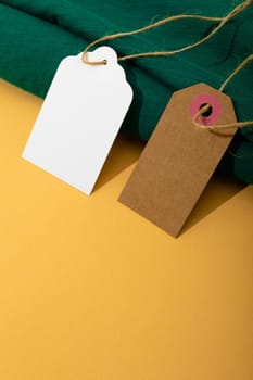 Composition of gift tags with copy space and green fabric on yellow background. christmas, gifts, tradition and celebration concept.