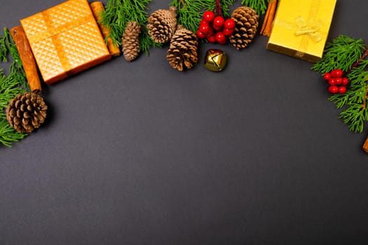 Composition of christmas decorations with presents, pine cones and copy space on black background. christmas, tradition and celebration concept.
