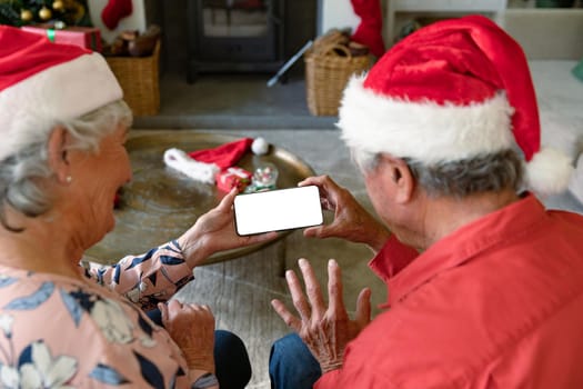 Caucasian senior couple wearing santa hats using smartphone with copy space at christmas time. christmas, festivity and communication technology.