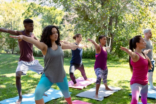 Group of diverse female and male people practicing yoga outdoors. fitness and healthy, active lifestyle.