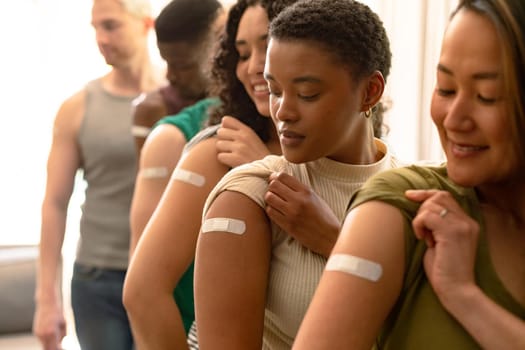 Group of diverse female and male friends showing plasters after vaccination. friendship, health and lifestyle during covid 19 pandemic.