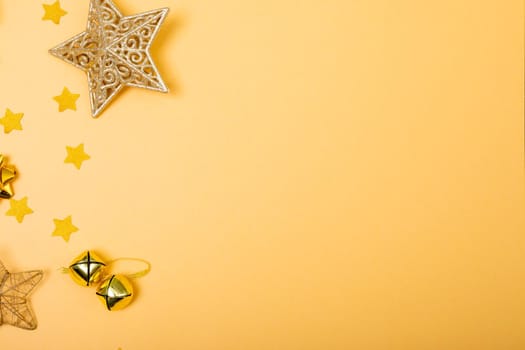Composition of christmas decorations with bells, stars and copy space on yellow background. christmas, tradition and celebration concept.