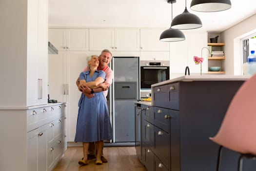 Happy caucasian senior couple dancing together in kitchen and having fun. healthy retirement lifestyle at home.