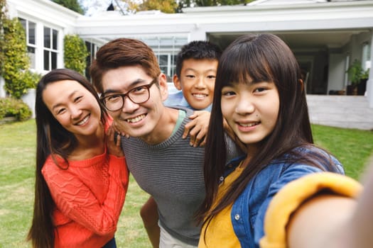 Portrait of happy asian parents, son and daughter smiling outdoors in garden. family enjoying leisure time together at home.