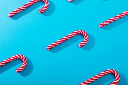 Composition of multiple rows of candy canes on blue background. christmas, tradition and celebration concept.