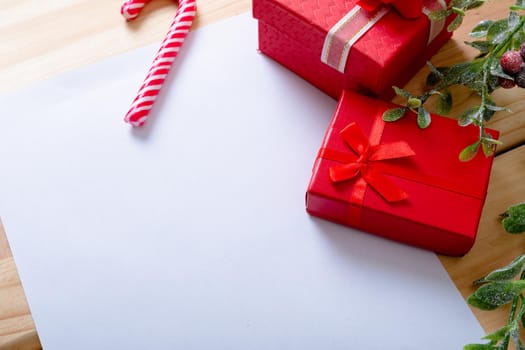 Composition of white card with copy space and candy cane with presents on wooden background. christmas, tradition and celebration concept.