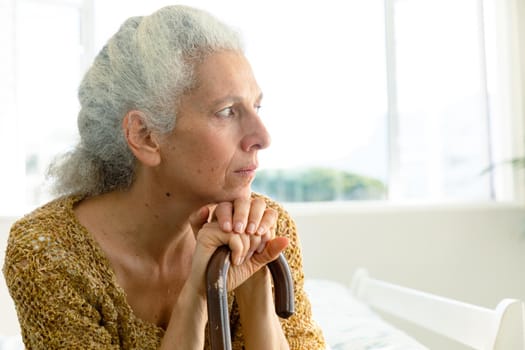 Profile of thoughtful caucasian senior woman holding rod and looking into distance. senior health and lifestyle at home.