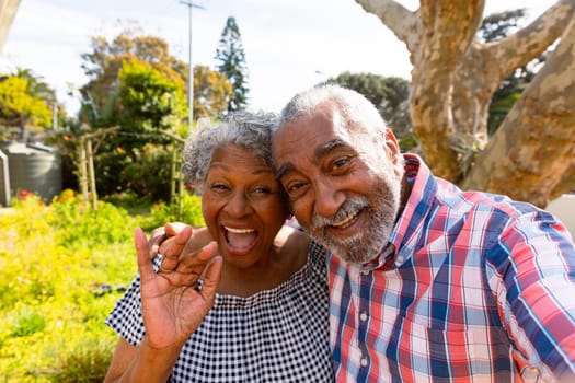 Happy african american senior couple taking selfie in garden. active retirement lifestyle at home and garden.