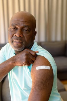 Portrait of african american senior man showing plaster after vaccination. senior health and lifestyle during covid 19 pandemic.