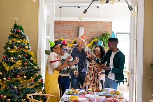 Group of happy diverse female and male friends with whistles and colorful hats celebrating new year. new year, festivities, celebrating at home with friends.