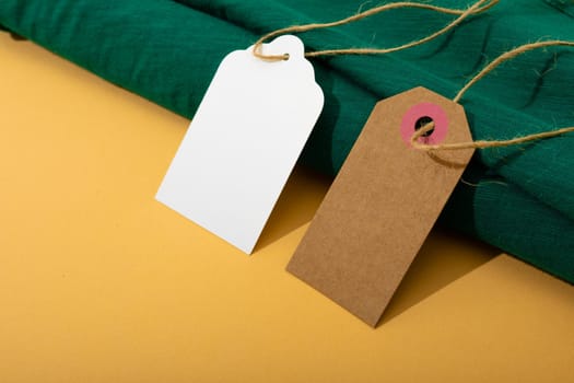 Composition of gift tags with copy space and green fabric on yellow background. christmas, gifts, tradition and celebration concept.