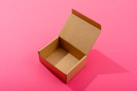 Composition of open empty cardboard gift box on pink background. christmas, gift, tradition and celebration concept.