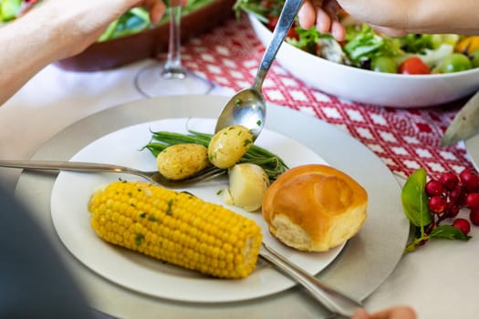 Hands of caucasian men putting potatoes on plate at christmas table. christmas, festivity, tradition and celebrating at home.