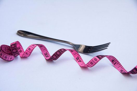 Measuring tape with fork background. Weight loss and fitness concept