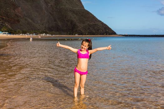 Cute little girl playing on sandy beach Tenerife, Canary Islands.