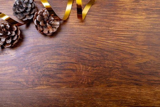 Composition of christmas decorations with pine cones and copy space on wooden background. christmas, tradition and celebration concept.