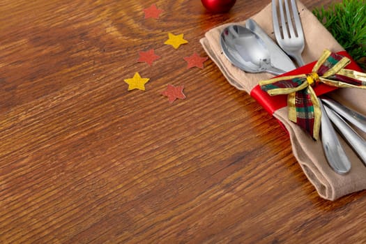 Composition of christmas decorations with cutlery and copy space on wooden background. christmas, tradition and celebration concept.