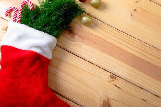 Composition of christmas stocking with fir tree, candy canes and copy space on wooden background. christmas, tradition and celebration concept.