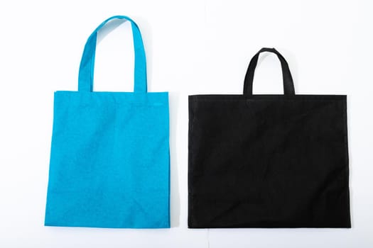 Composition of empty blue and black canvas shopping bags lying flat on white background. shopping and retail concept.