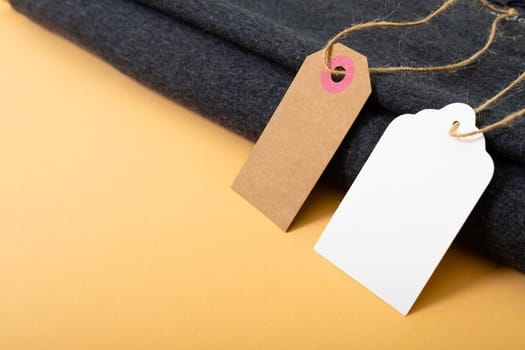 Composition of gift tags with copy space and black fabric on yellow background. christmas, gifts, tradition and celebration concept.