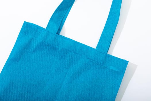 Composition of empty blue canvas shopping bag lying flat on white background. shopping and retail concept.