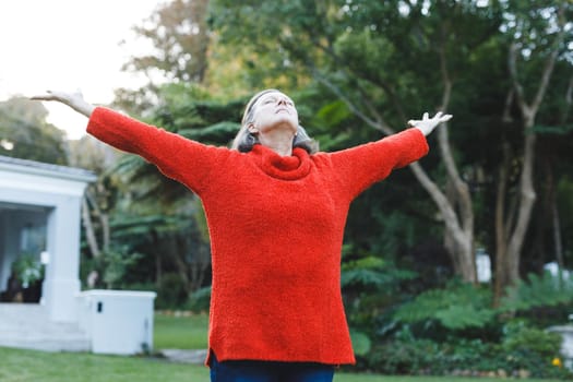 Happy senior caucasian woman with arms outstretched in garden. healthy retirement lifestyle, spending time self caring at home.
