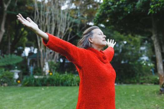 Happy senior caucasian woman with arms outstretched in garden. healthy retirement lifestyle, spending time self caring at home.