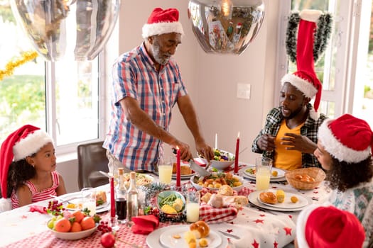 Happy multi generation family wearing santa hats, having christmas meal. family christmas time and festivity together at home.