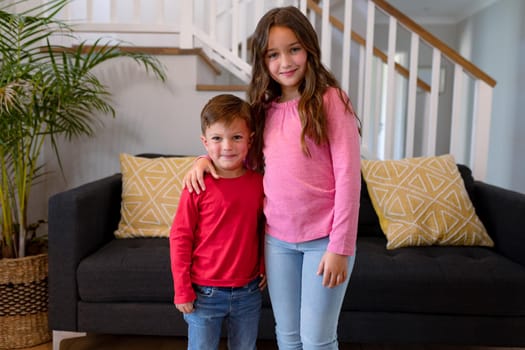 Happy caucasian siblings standing at home and looking at camera. childhood, leisure and spending time at home.