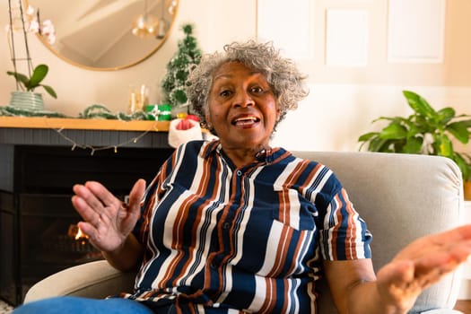 African american senior woman sitting in armchair, gesturing and talking. healthy retirement lifestyle at home.